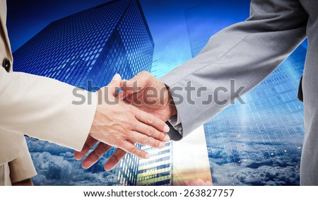 Close up of business people shaking their hands against low angle view of skyscrapers at sunset