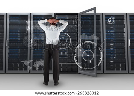Businessman standing back to the camera with hands on head against server towers