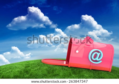 Red email post box against green field under blue sky
