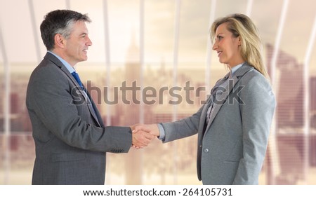 Pleased businessman shaking the hand of content businesswoman against room with large window looking on city