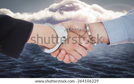 Business people in handcuffs shaking hands against calm sea with lighthouse