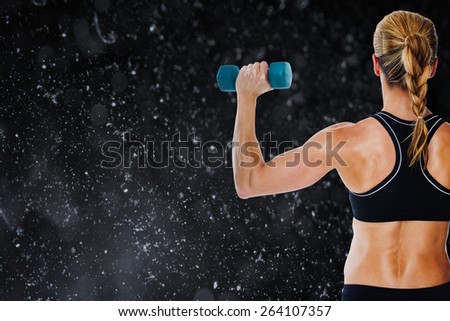 Female bodybuilder holding a blue dumbbell against black background