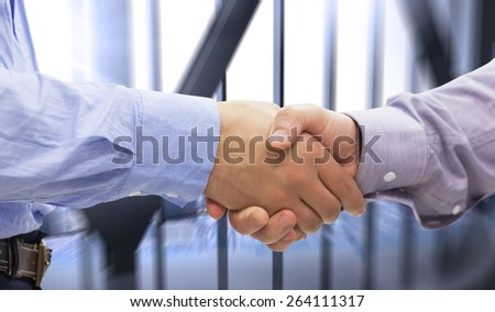 Two men shaking hands against room with large window looking on city