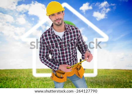 Smiling handyman holding tape measure against green light bulb with white house outline