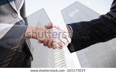 Close up of two businesspeople shaking their hands against skyscraper