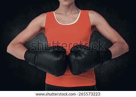 Close-up mid section of a determined female boxer against dark background