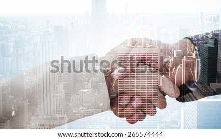 Close up on partners shaking hands against city skyline