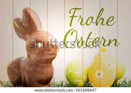 frohe ostern against chocolate bunny rabbit and three easter eggs