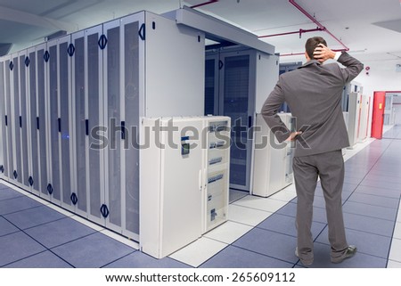 Young businessman standing back to camera scratching his head against data center
