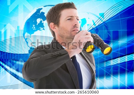 Focused handsome businessman holding binoculars against global business graphic in blue