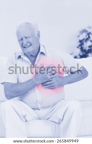 Aged man suffering with heart pain on a sofa