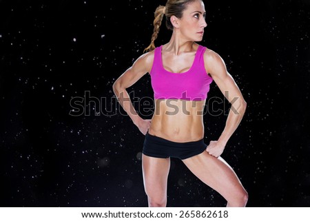 Female bodybuilder posing in sports bra and shorts against black background