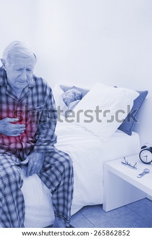 Old man suffering with belly pain in the bedroom