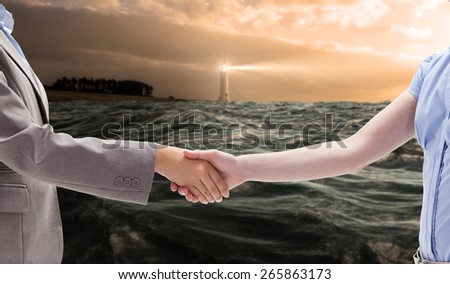 Handshake between two women against stormy sea with lighthouse