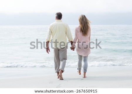 Happy couple walking by the sea at the beach
