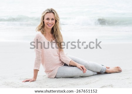 Smiling pretty blonde relaxing on the sand at the beach