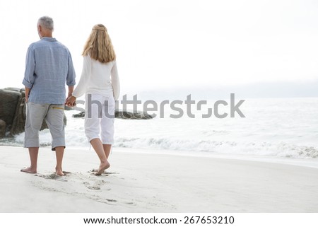 Happy couple walking by the sea at the beach