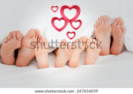 Family on the bed at home with their feet showing against pink hearts