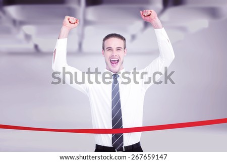 Businessman crossing the finish line and cheering against white abstract room