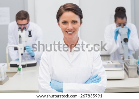 Happy scientist smiling at camera with arms crossed in the laboratory
