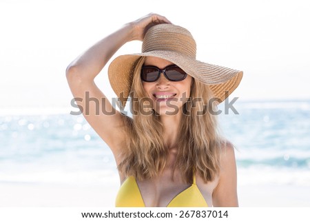 Smiling pretty blonde wearing sun glasses and looking at camera at the beach