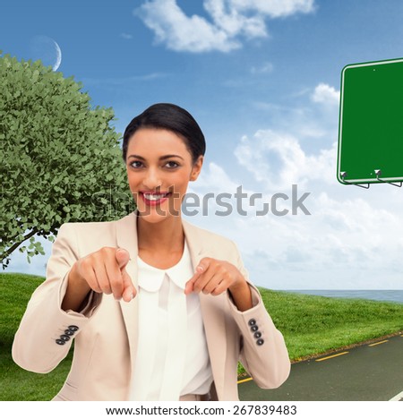Smiling businesswoman pointing at the camera against road leading out to the horizon