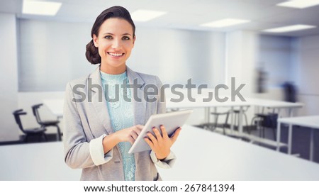 Brunette using tablet pc against empty class room