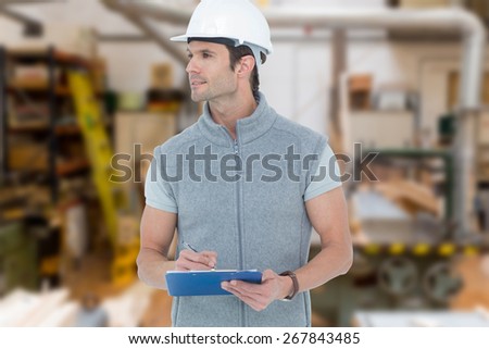 Architect writing on clip board against workshop