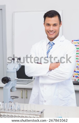 Happy scientist smiling at camera with arms crossed in the laboratory