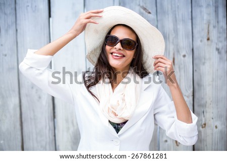 Smiling beautiful brunette wearing straw hat and sun glasses on wooden plank background