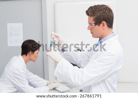 Scientists working attentively with test tube and computer in laboratory