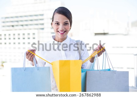 Happy woman looking inside shopping bags outside