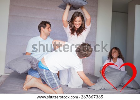 Family having a pillow fight on the bed against heart