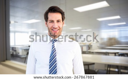 Smiling businessman standing with hands in pockets against empty class room