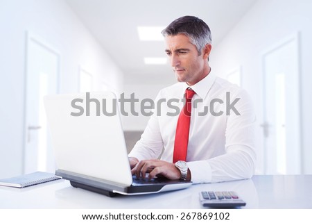 Businessman using laptop against bright hallway with several doors