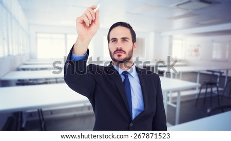 Businessman holding a chalk and writing something against empty class room