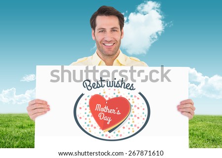 Attractive man smiling and holding poster against field and sky