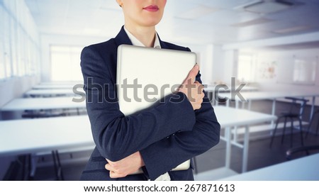 Businesswoman holding laptop against empty class room