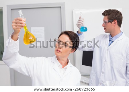 Scientists looking attentively at beakers in laboratory
