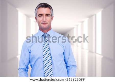 Smiling businessman in suit with hands in pocket posing against digitally generated room