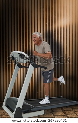 Full length of a senior man running on a treadmill against dark grey room