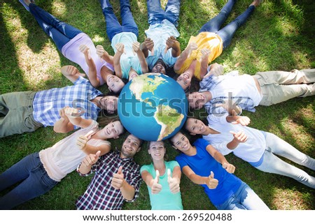 Earth against happy friends in the park lying in circle