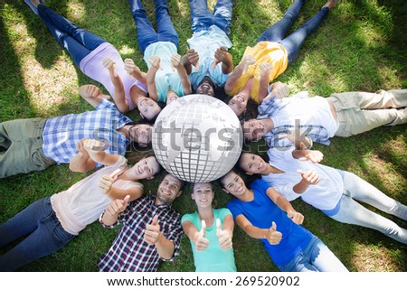 Silver earth against happy friends in the park lying in circle