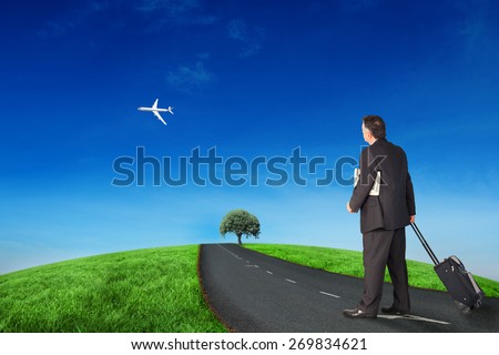 Mature businessman pulling his suitcase against road leading out to the horizon