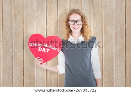 Geeky hipster holding heart card against wooden planks