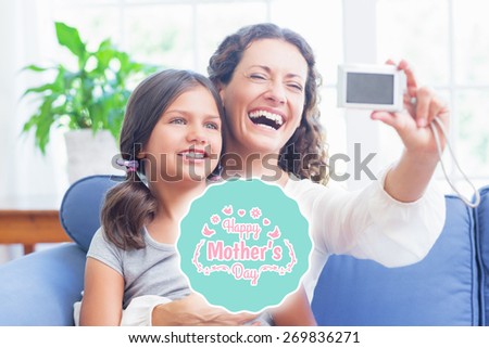 mothers day greeting against happy mother and daughter sitting on the couch and taking selfie