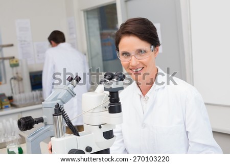 Scientists working with microscope and computer in laboratory