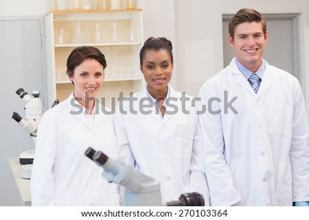 Smiling scientists team looking at camera in the laboratory