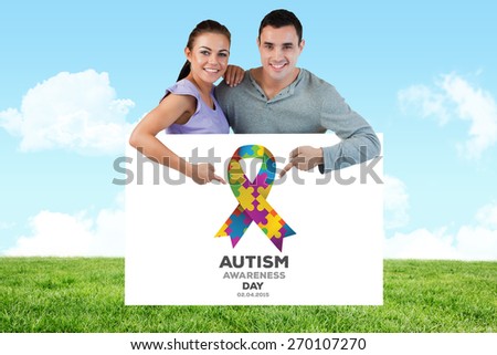 Young couple pointing at advertisement below them against field and sky