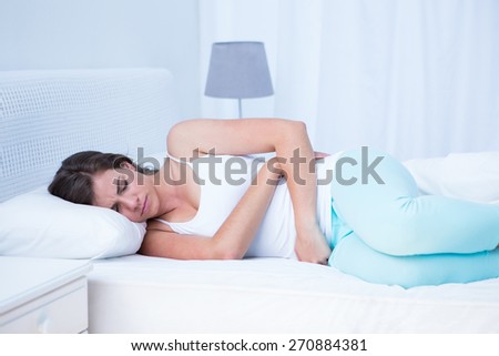 Pretty woman with stomach pain at home in the bedroom